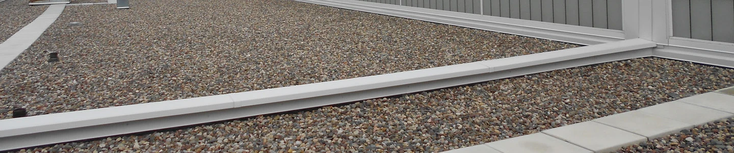 Stone ballast covering a low-slope commercial roof beside raised metal flashings