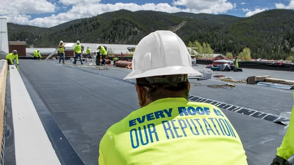 Equipo de Arapahoe Roofing instalando membrana EPDM oscura en Summit High School, Colorado