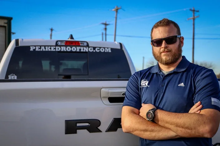 Peaked Roofing team member beside a company truck