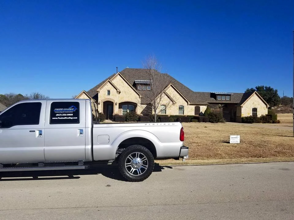 A Peaked Roofing vehicle outside a home.